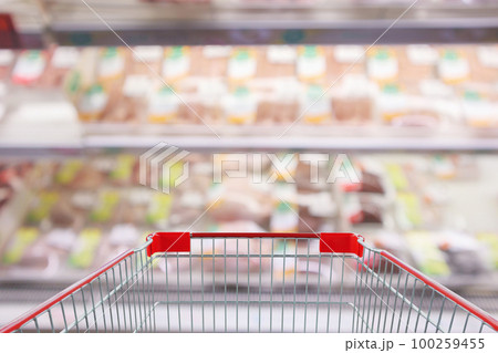 Empty red shopping cart with Abstract fresh meat shelves in supermarket grocery store blurred defocused background with bokeh light 100259455