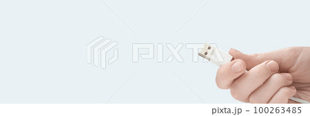 Hand holding white USB cable isolated on white background. Photo with copy space. 100263485