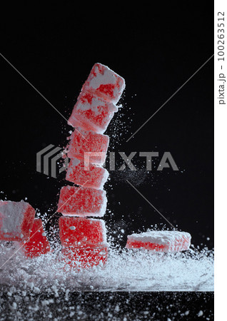 Strawberry red marmalade jelly candy's covered with powder sugar on black background. Photo with copy space. The concept of Christmas sweets. 100263512