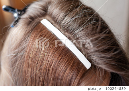 Hair ribbons for extensions on a woman's head at home. Hair ribbons for extensions on a woman's head at home. 100264889