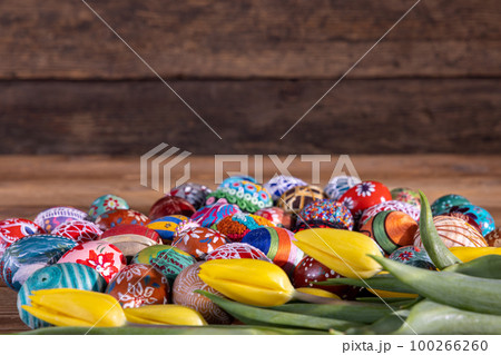 A side view of the yellow tulips and colorful Easter eggs lying around. 100266260