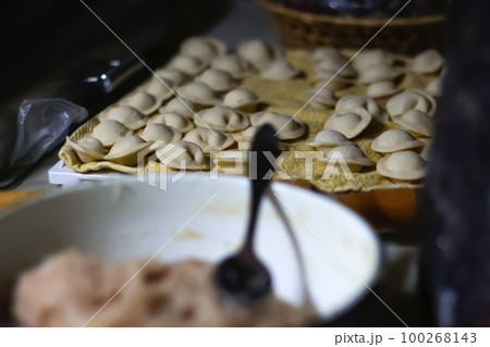 Raw homemade meat dumplings with onions. russian pelmeni on the dark lifestyle background. Meat dumplings, ravioli. Out of focus 100268143