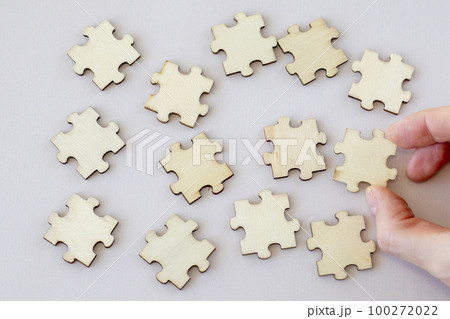 Set of wooden puzzles on a beige background with a woman's hand. 100272022