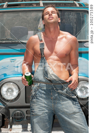 attractive athletic young man leaning on his car drinking beer attractive athletic young man leaning on his car drinking beer 100275589
