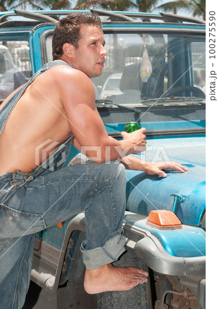 attractive athletic young man leaning on his car drinking beer attractive athletic young man leaning on his car drinking beer 100275590