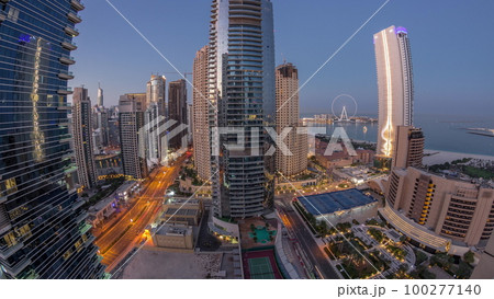 Panoramic view of the Dubai Marina and JBR area and the famous Ferris Wheel aerial night to day timelapse 100277140