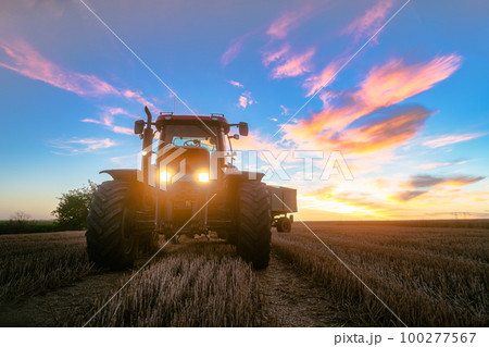 Tractor on harvested grain field during dusk 100277567