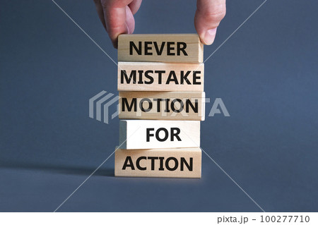 Mistake or action symbol. Concept words Never mistake motion for action on wooden blocks. Businessman hand. Beautiful grey table grey background. Business mistake or action concept. Copy space. 100277710