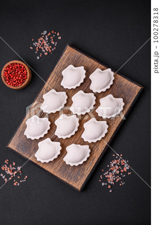 Raw frozen stuffed dumplings on a wooden cutting board 100278318