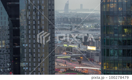 Villas and famous hotel in the horizon line from Dubai downtown with big intersection aerial day to night timelapse 100278479
