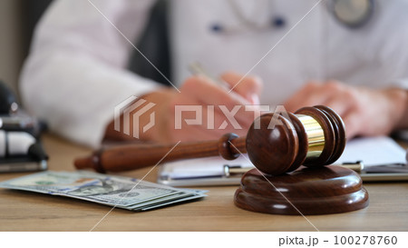 Judge gavel on hospital desk and doctor making notes in documents. Judge gavel on hospital desk and doctor making notes in documents. 100278760