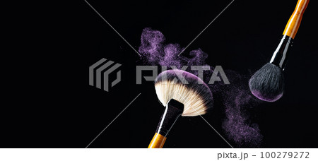 Makeup concept with a professional makeup brushes with glowing purple eye shadow isolated on black background. Makeup concept with a professional makeup brushes with glowing purple eye shadow isolated on black background. 100279272