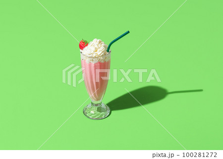 Milkshake glass minimalist on a green background. Homemade strawberries milkshake 100281272