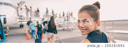 Travel woman boarding airplane at airport. Happy young Asian lady tourist walking on outside tarmac leaving for vacation trip panoramic banner 100281691
