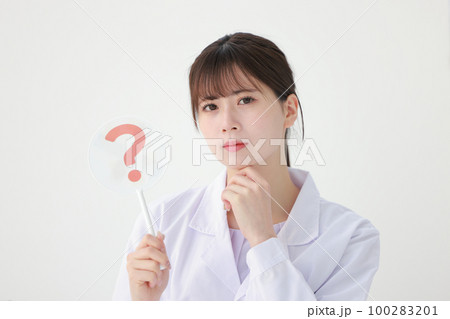 はてなのプレートを持ちあごに手を当てる白衣の若い女性1 100283201
