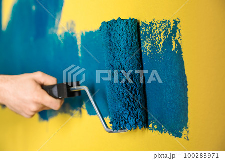 Man painting yellow wall with blue dye, closeup Man painting yellow wall with blue dye, closeup 100283971