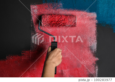 Woman painting grey wall with pink dye, closeup 100283977