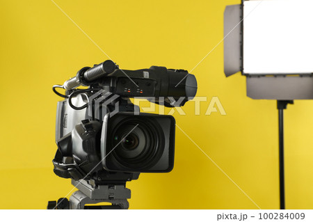 Professional video camera and lighting equipment on yellow background Professional video camera and lighting equipment on yellow background 100284009