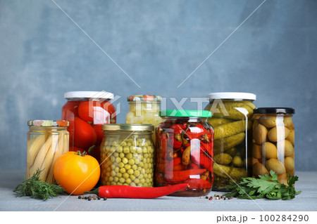 Glass jars with different pickled vegetables on table 100284290
