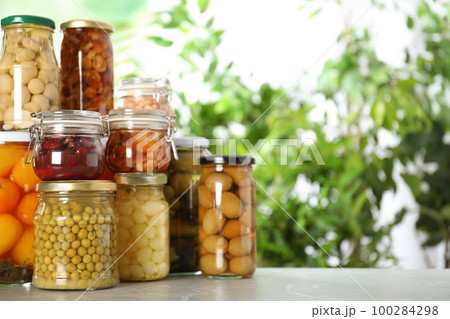 Glass jars of different pickled vegetables on marble table. Space for text Glass jars of different pickled vegetables on marble table. Space for text 100284298