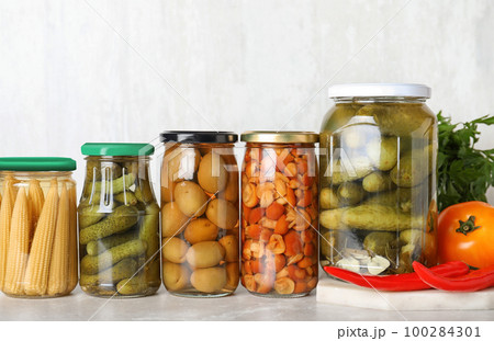 Glass jars with different pickled vegetables on light marble table Glass jars with different pickled vegetables on light marble table 100284301