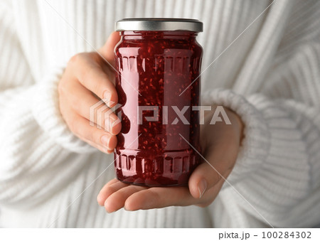 Woman with jar of raspberry jam, closeup Woman with jar of raspberry jam, closeup 100284302