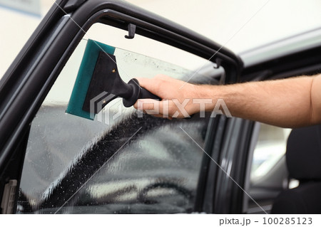 Worker washing tinted car window in workshop, closeup 100285123
