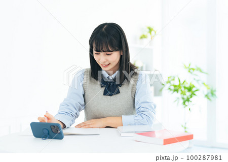スマホを見ながら勉強する女子学生 スマホを見ながら勉強する女子学生 100287981