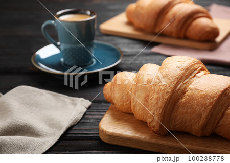 Tasty fresh croissants and coffee on black wooden table, closeup 100288778