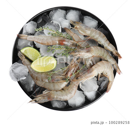 Plate with raw shrimps, lime slices, thyme and ice isolated on white, top view 100289258
