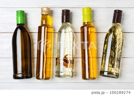 Different sorts of cooking oil in bottles on white wooden table, flat lay Different sorts of cooking oil in bottles on white wooden table, flat lay 100289274