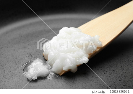 Frying pan with coconut oil and wooden spatula, closeup. Healthy cooking 100289361