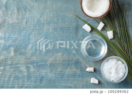Flat lay composition with coconut oil on light blue wooden table, space for text 100289362
