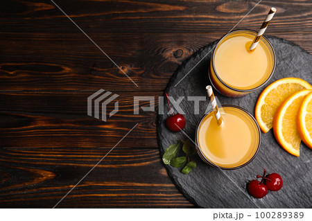 Fresh alcoholic Tequila Sunrise cocktail on wooden table, top view. Space for text Fresh alcoholic Tequila Sunrise cocktail on wooden table, top view. Space for text 100289389