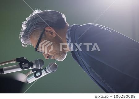謝罪会見風のグレイヘアの男性 100290088