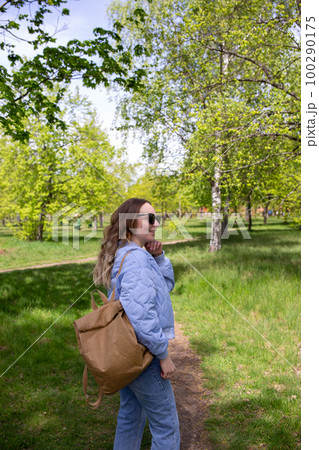 A young girl walks alone in the park with a backpack A young girl walks alone in the park with a backpack 100290175