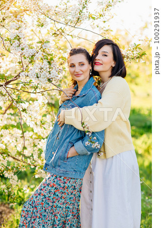 two attractive women hugging in a spring garden.  100291937