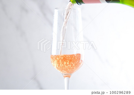 よく冷えたロゼのシャンパン（スパークリングワイン）をフルートグラスに注ぐ 100296289