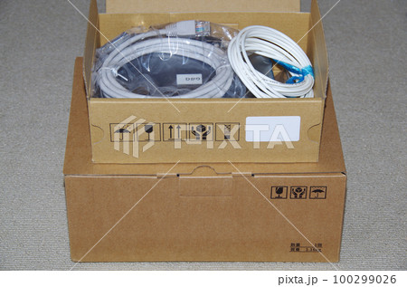 電話会社から自宅に届いた光回線機器の箱を開梱中のイメージ 100299026