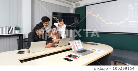 Group of business people in suit analyze stock information in the meeting room. Business executives team meeting in modern office with laptop computer, tablet, mobile phone on table. 100299154