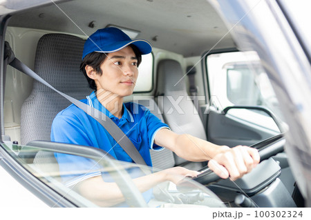 トラックを運転する若い男性ドライバー トラックを運転する若い男性ドライバー 100302324
