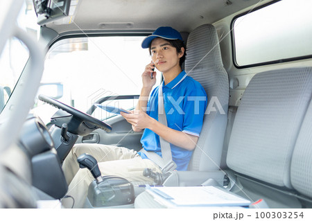 運転席でスマホを使うドライバーの男性 運転席でスマホを使うドライバーの男性 100303254