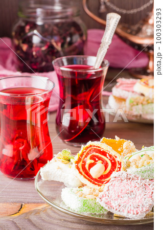 Traditional Turkish Delight. on a saucer and hot karkade in cups on a wooden table Traditional Turkish Delight. on a saucer and hot karkade in cups on a wooden table 100303293
