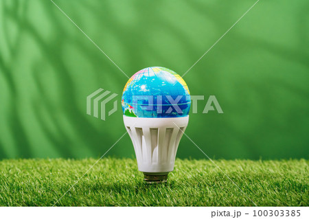 Globe in LED light bulb in green grass ecological background. Green energy efficient saving and innovative smart house solutions. Sustainable consumption and lifestyle. Earth Day Globe in LED light bulb in green grass ecological background. Green energy efficient saving and innovative smart house solutions. Sustainable consumption and lifestyle. Earth Day 100303385
