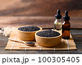 Black sesame seed and oil on wooden background, Food ingredients in Asian cuisine 100305405