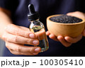 Black sesame seed and oil holding by hand, Food ingredients in Asian cuisine 100305410