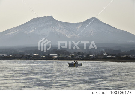 早春の北海道森町で残雪の駒ヶ岳と漁をする漁船の風景を撮影 100306128