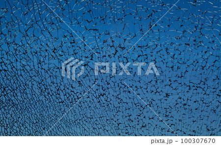 Dark blue broken cracked shattered window glass with black cracks Dark blue broken cracked shattered window glass with black cracks 100307670