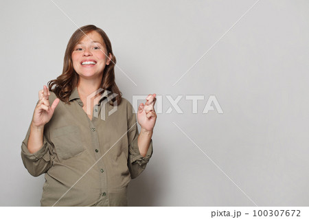 Happy pregnancy concept. Cute pregnant woman crossing her fingers and smiling Happy pregnancy concept. Cute pregnant woman crossing her fingers and smiling 100307672