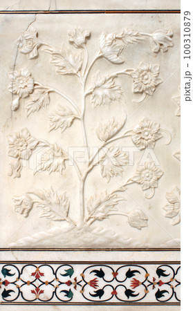 Ancient carved bas-relief with flowers on marble. Beautiful ornament with carved flower on the wall of the famous mausoleum Taj Mahal, India 100310879